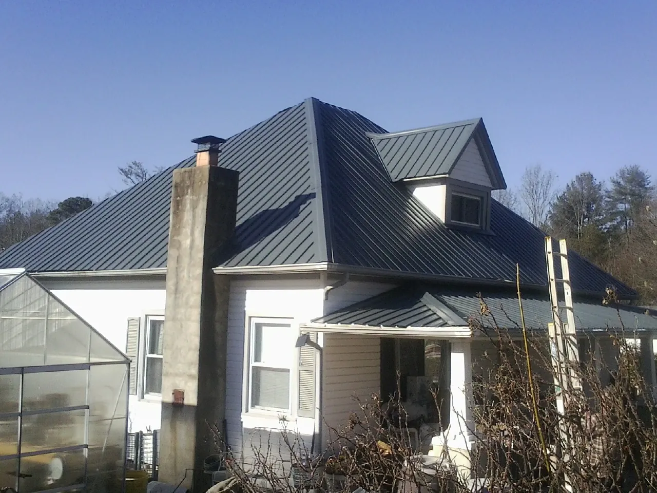 Dark blue standing seam metal roof on a white farmhouse with dormer — Slate & Tile Roof Repair by Roofing Brothers in Hood River
