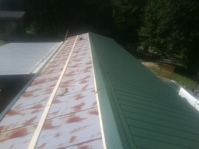 Old rusted panels beside newly installed green metal roofing — Wind Damage Roof Repair by Roofing Brothers in Hood River