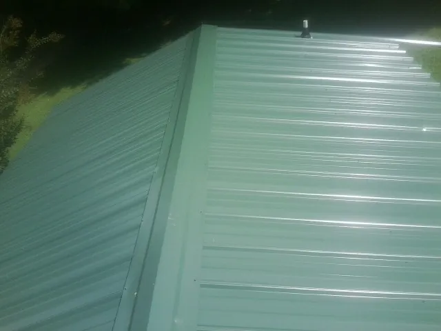 New green metal panels meeting at the ridge of a roof — Flat Roof Repair work by our crew in Hood River