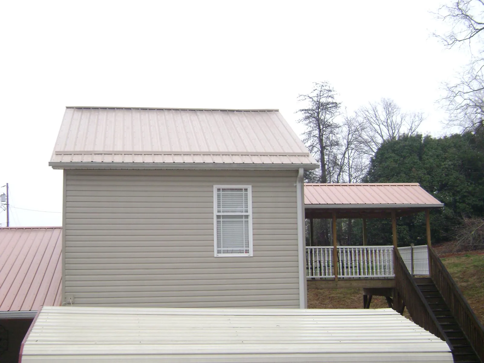 Tan metal roofs on a two story addition and attached porch, from a Roof Replacement job in Hood River
