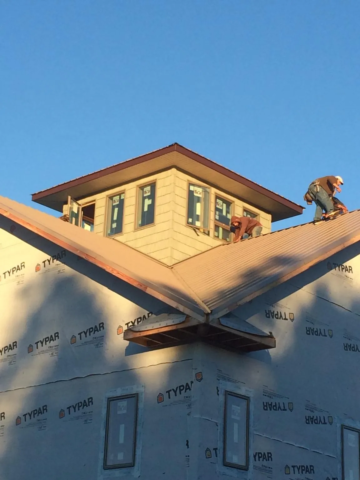 Roofers working around a rooftop cupola on a new metal roof at sunset — Roof Waterproofing in Hood River by Roofing Brothers